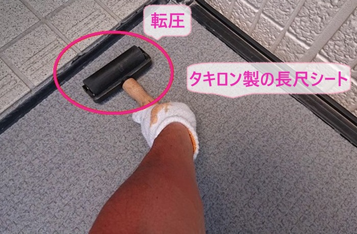 外部廊下と階段のリフォームでタキロン製の長尺シートをローラーで転圧している様子