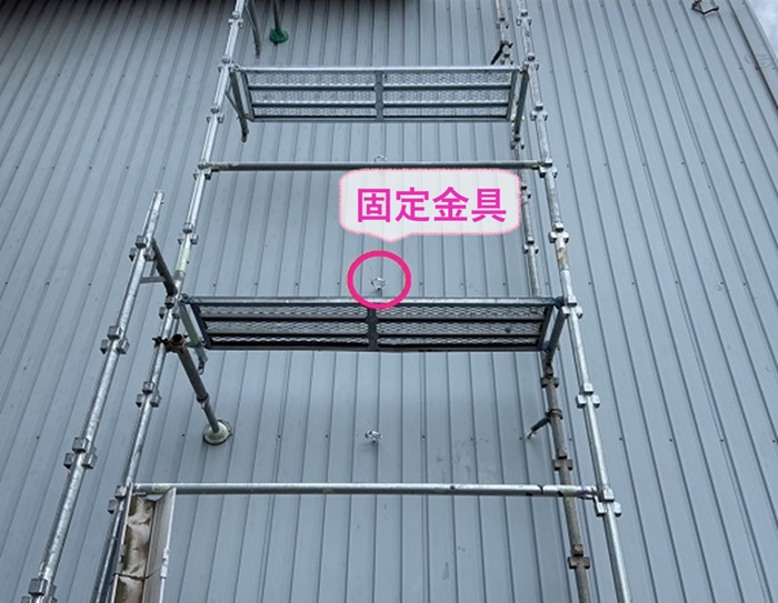 倉庫の排水パイプの交換で新しい竪樋の固定金具を取り付けている様子