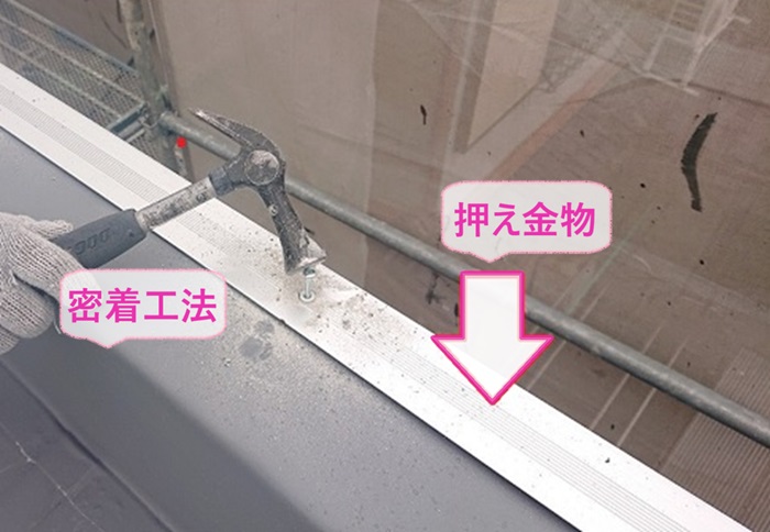 陸屋根シート防水工事で立ち上がり部分は密着工法でシート防水を貼って押え金物を取り付けている様子