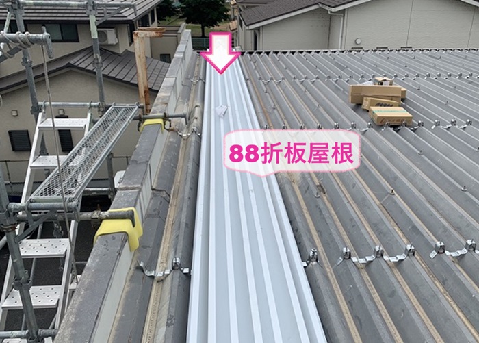 商業施設の雨漏り修理で既存の折半屋根の上に新しい折半屋根をクレーンで上げている様子