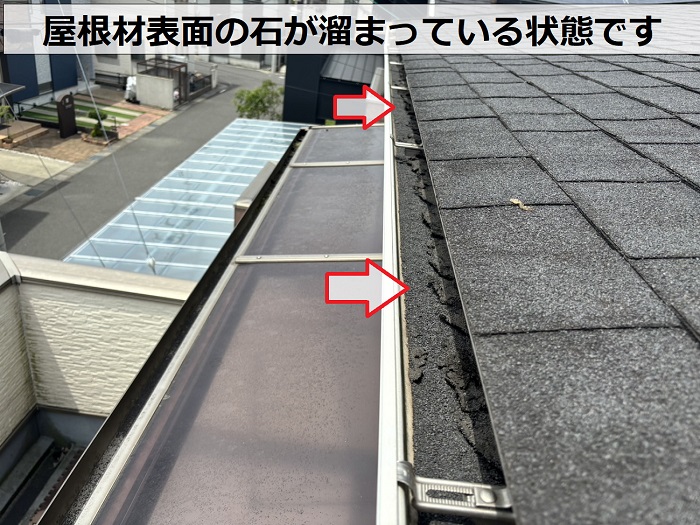 アスファルトシングル屋根の石が雨樋に詰まっている様子