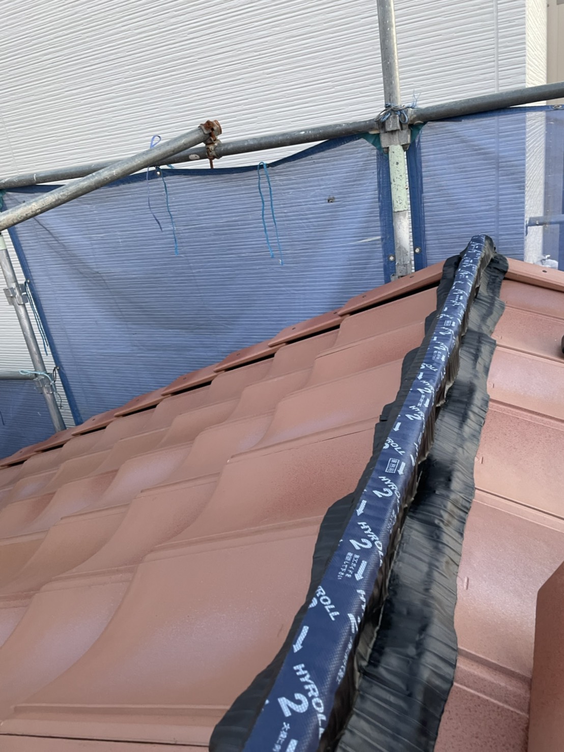 三木市での屋根葺き替え工事「通気工法」で棟に防水テープを貼っている様子