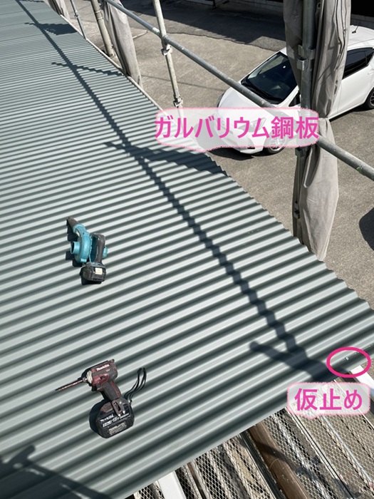 神戸市西区の波板スレート屋根の交換でガルバリウム鋼板を小さいビスで仮止めしながら取り付けている様子
