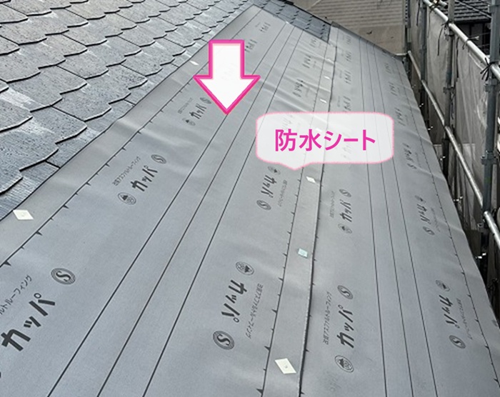 ３階建て住宅の屋根重ね葺き工事で防水シートを貼っている様子