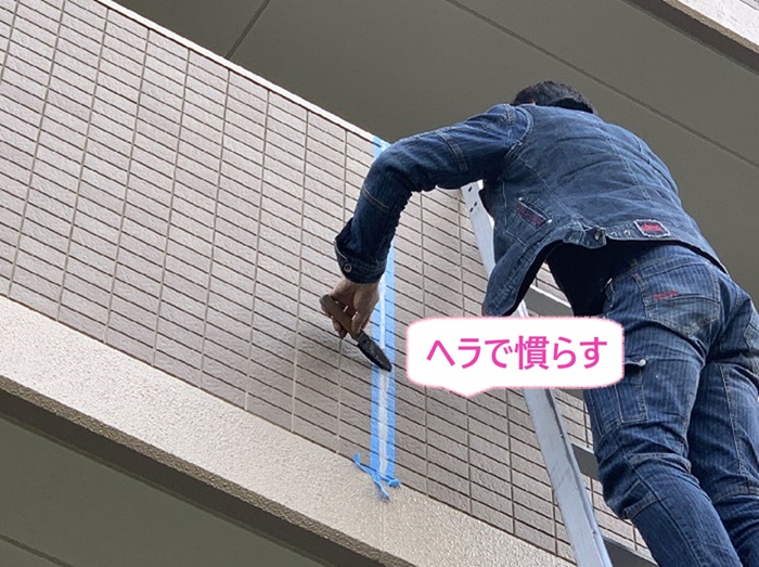 神戸市西区の集合住宅で外壁タイルにシーリング材をヘラで慣らしている様子