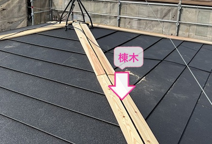 緩傾斜な屋根の重ね葺き工事で棟の部分に棟木を取り付けている様子