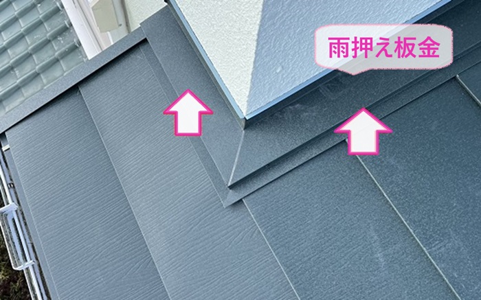 瓦屋根と複合したカラーベスト屋根の壁際に雨押さえ板金を取り付けている様子