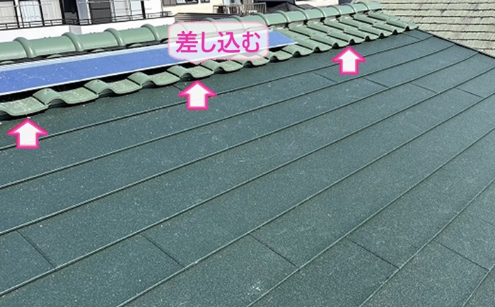 カラーベスト屋根のカバー工事で瓦屋根の隙間に断熱屋根材を差し込んで葺いている様子
