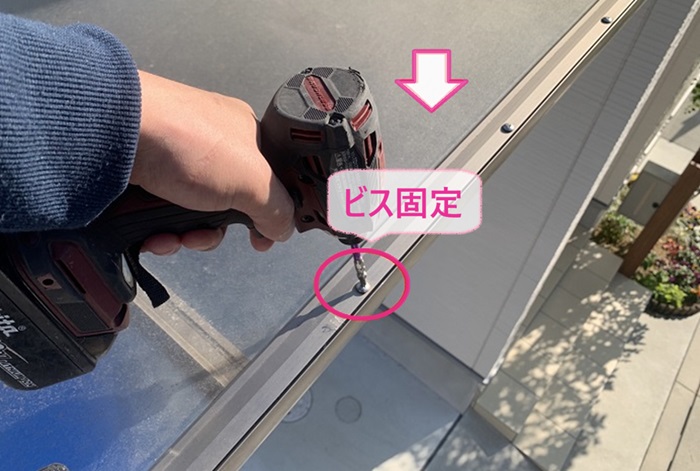 エアコン室外機の取り付けでガレージ屋根にアクリルを戻してビス固定している様子