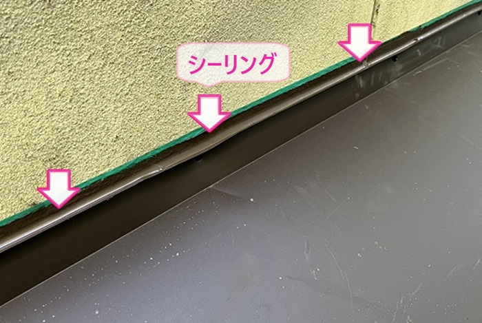 窓上の小庇の板金補修で壁際にシーリングを打っている様子