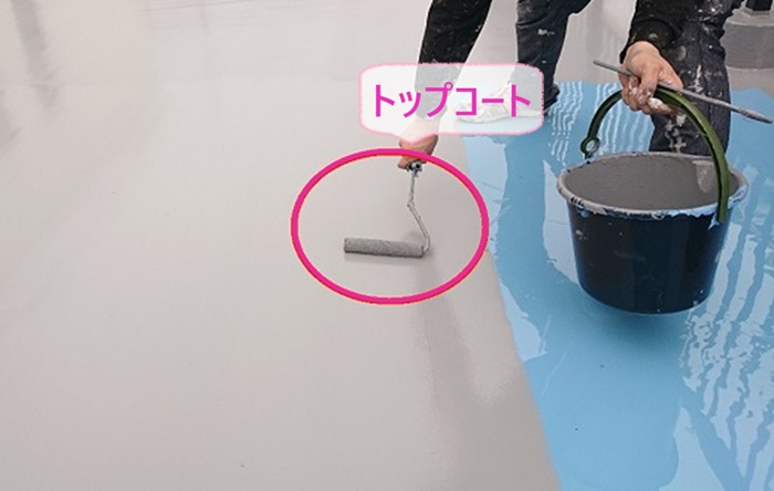 陸屋根シート防水の改修工事でトップコートを塗っている様子