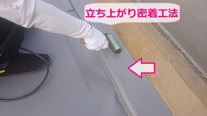 神戸市西区での陸屋根防水工事で立ち上がりに塩ビシートを貼っている様子