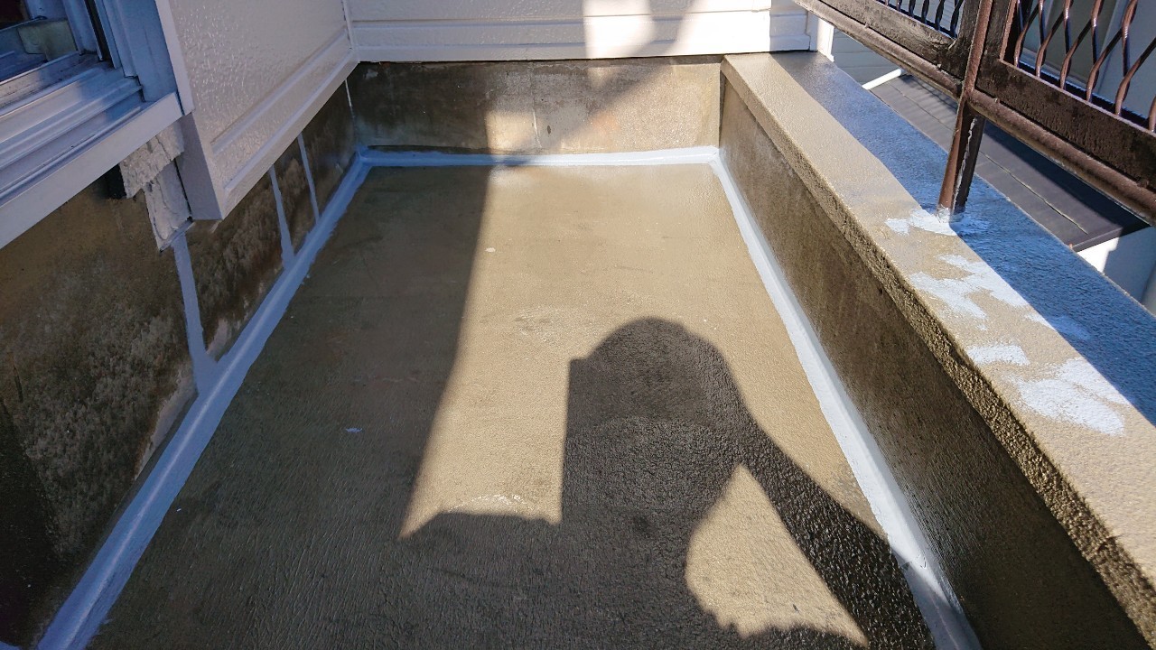 播磨町での雨漏り修理でひび割れたベランダ床にコーキングで補修している様子