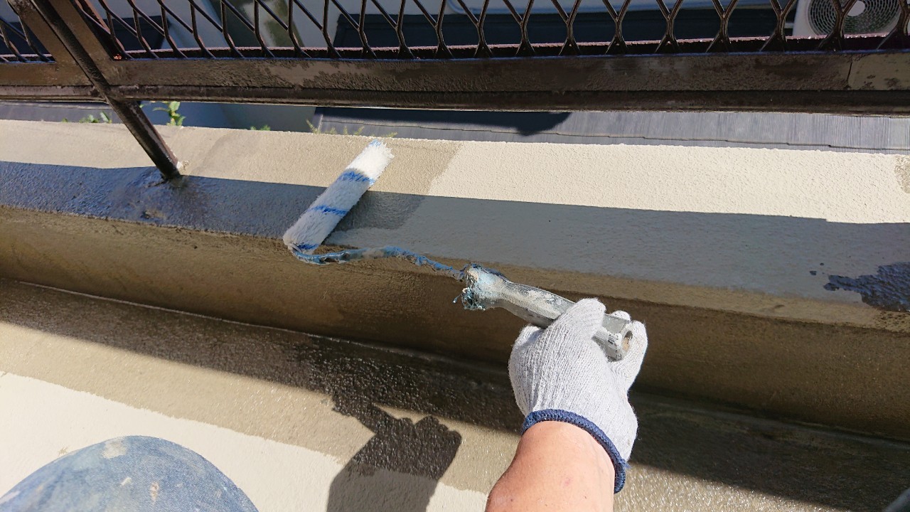 雨漏り修理でひび割れたベランダ床に防水工事を行うためプライマーを塗っている様子