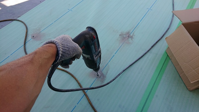 屋上の塩ビシート防水工事で下穴を開けている様子