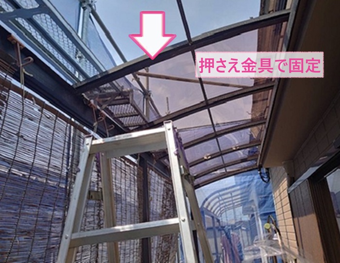 ベランダ屋根の張り替えでポリカ板を押さえ金具でしっかり固定している様子