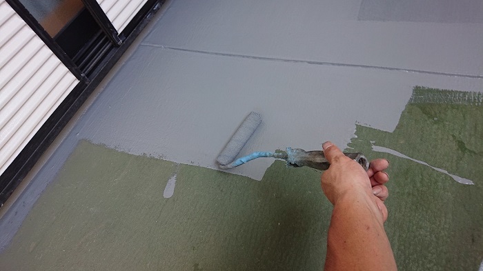 ベランダ床の修理工事でトップコートを塗っている様子