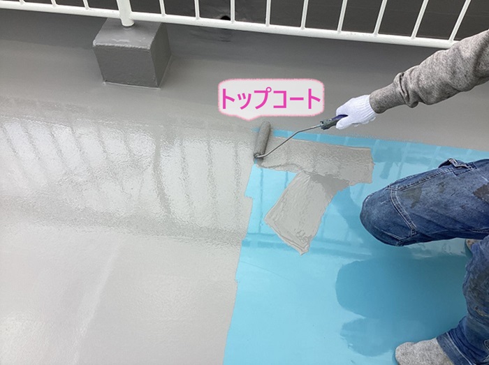 神戸市北区の3階建てマンションの陸屋根でトップコートを塗っている様子