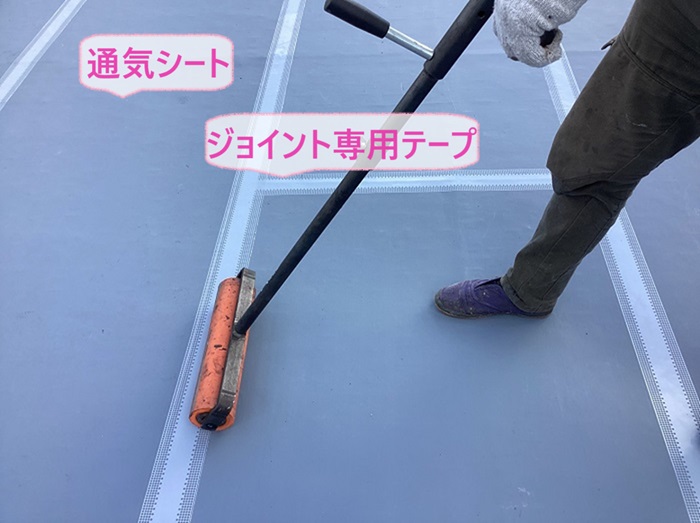 神戸市北区の3階建てマンションの陸屋根で通気シートを貼ってジョイント部分に専用のテープを貼っている様子