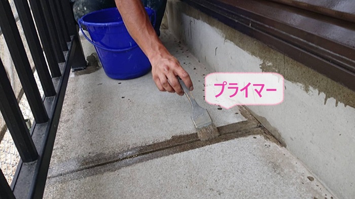 神戸市中央区の防水工事するバルコニー床にプライマーを塗っている様子