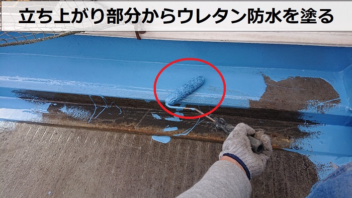 神戸市中央区の陸屋根防水工事で立ち上がり部分にウレタン防水を塗っている様子