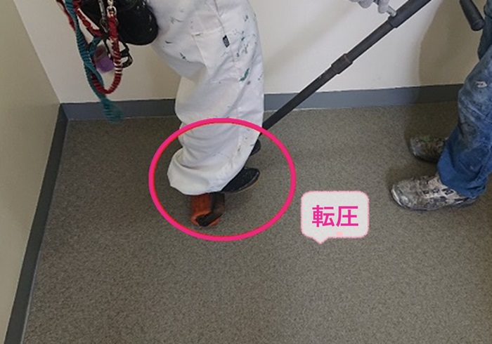 明石市で共用廊下に貼った長尺シートをローラーでしっかり転圧している様子