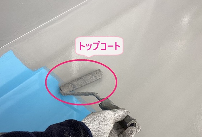 コンクリート素地のベランダ床の防水工事でトップコートを塗っている様子