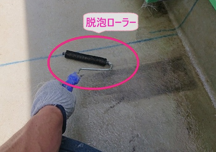 高耐久なベランダFRP防水の改修工事で脱泡ローラーで脱泡作業をしている様子