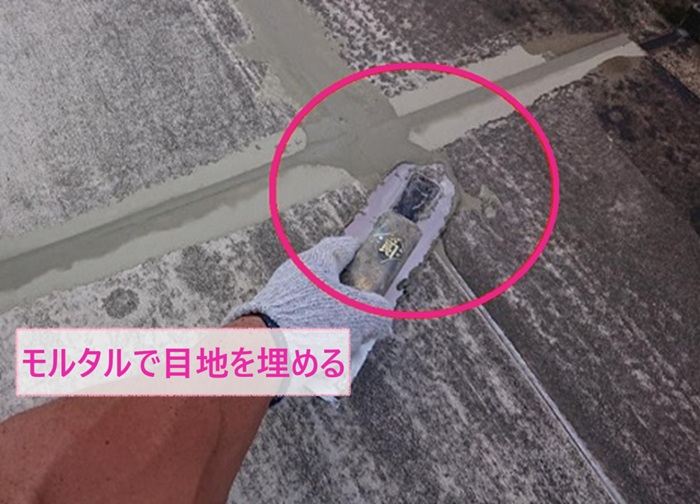 集合住宅の長尺シート貼りで共用廊下の目地をモルタルで埋めている様子