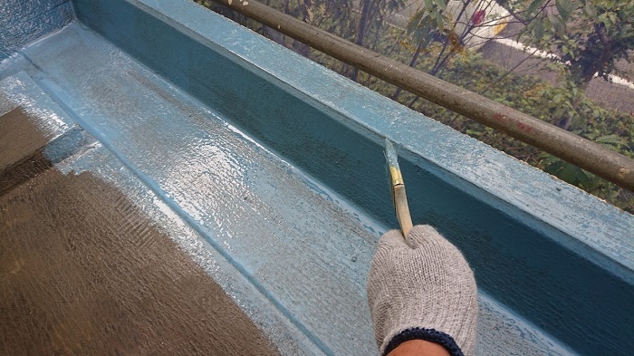 屋上防水工事で立ち上がりにウレタン防水を塗っている様子