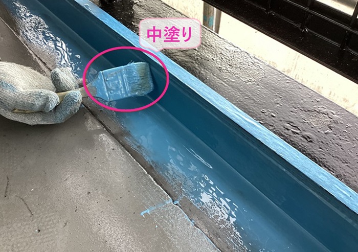 集合住宅のベランダ防水工事で中塗りしている様子