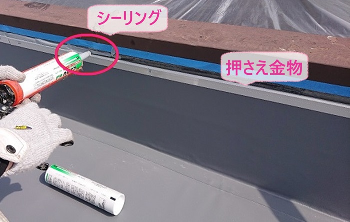 屋上のゴムシート防水貼り替えで押さえ金物を取り付けてシーリングを塗っている様子