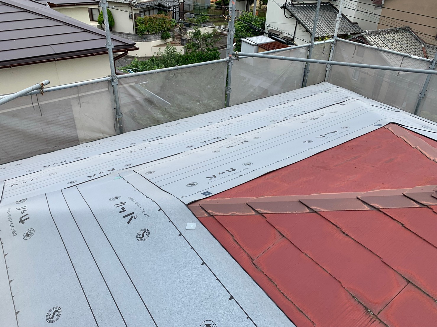 屋根重ね葺き工事を行うために防水シートを貼っている様子