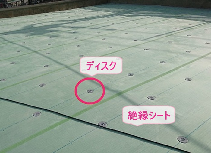 屋上リニューアル工事で絶縁シートを敷いてディスクを取り付けている様子