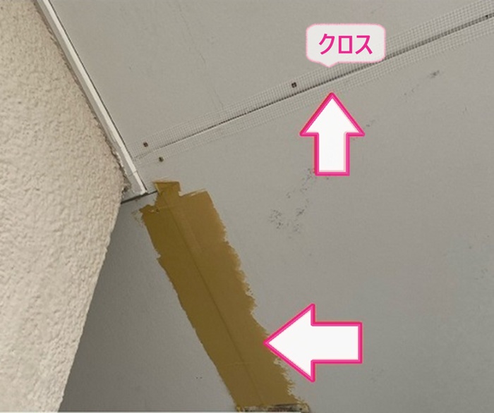 軒裏の修繕工事でケイカル板のジョイントにクロスを貼っている様子