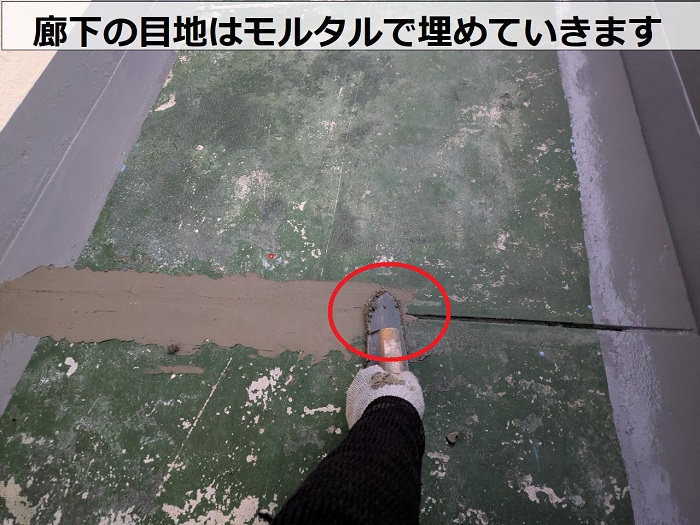 神戸市長田区で共用廊下の長尺シートをタキロンQAに貼り替えで目地にモルタルを埋めている様子