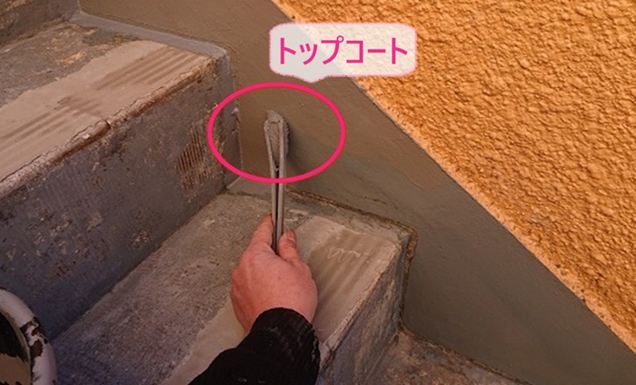 3階建てマンションの階段補修でサイドにトップコートを塗っている様子