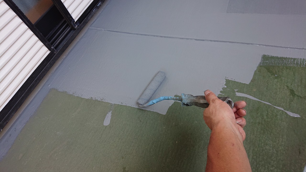 ベランダ床のメンテナンスでローラーを使用してトップコートを塗っている様子