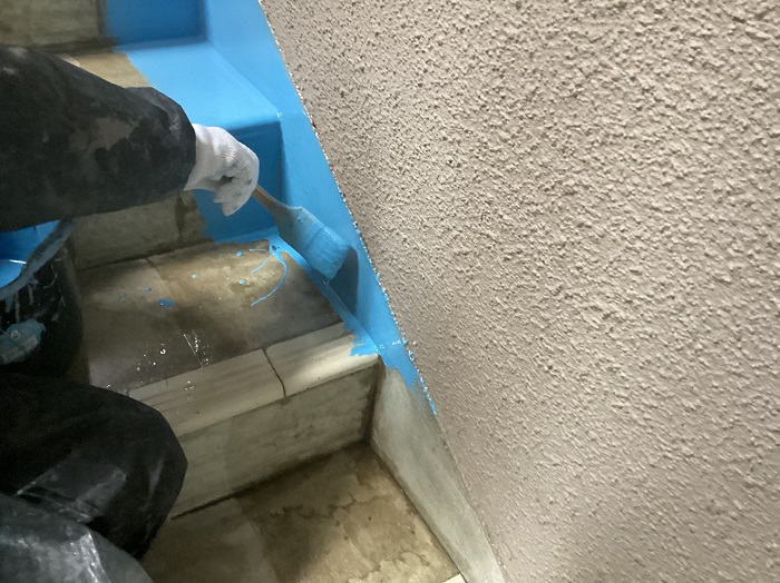 マンションの階段の縁にウレタン防水を塗っている様子