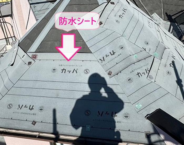 鋭角で多面なコロニアル屋根の重ね施工で防水シートを貼っている様子