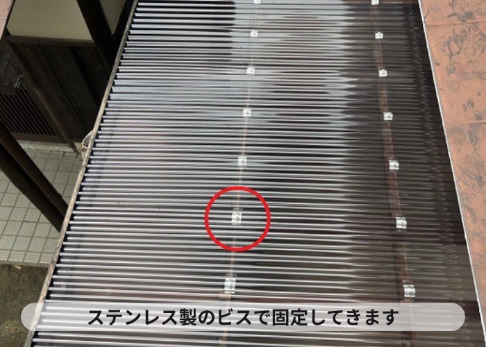西宮市　劣化したストックヤードの屋根交換でポリカ波板をステンレス製のビスで固定している様子