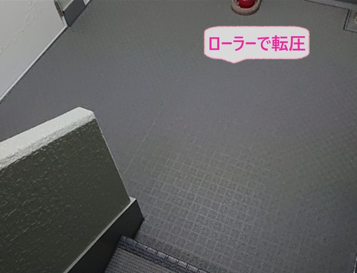 アパート共用部の床改修で長尺シートをローラーで転圧している様子